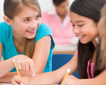 Three elementary school pupils talking in classroom