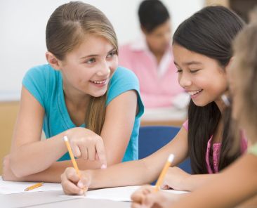 Three elementary school pupils talking in classroom