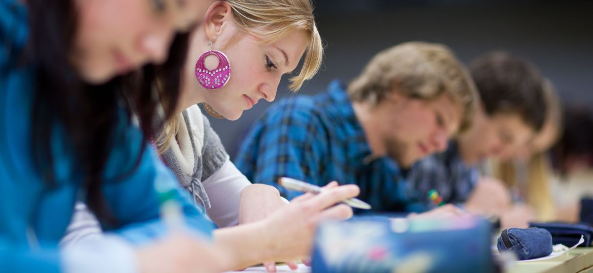 Pretty female college student sitting in a classroom full of stu